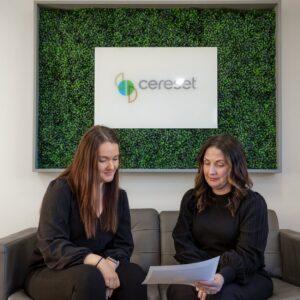 two women discussing in front of plantwall sign in Cereset Fergus Falls lobby